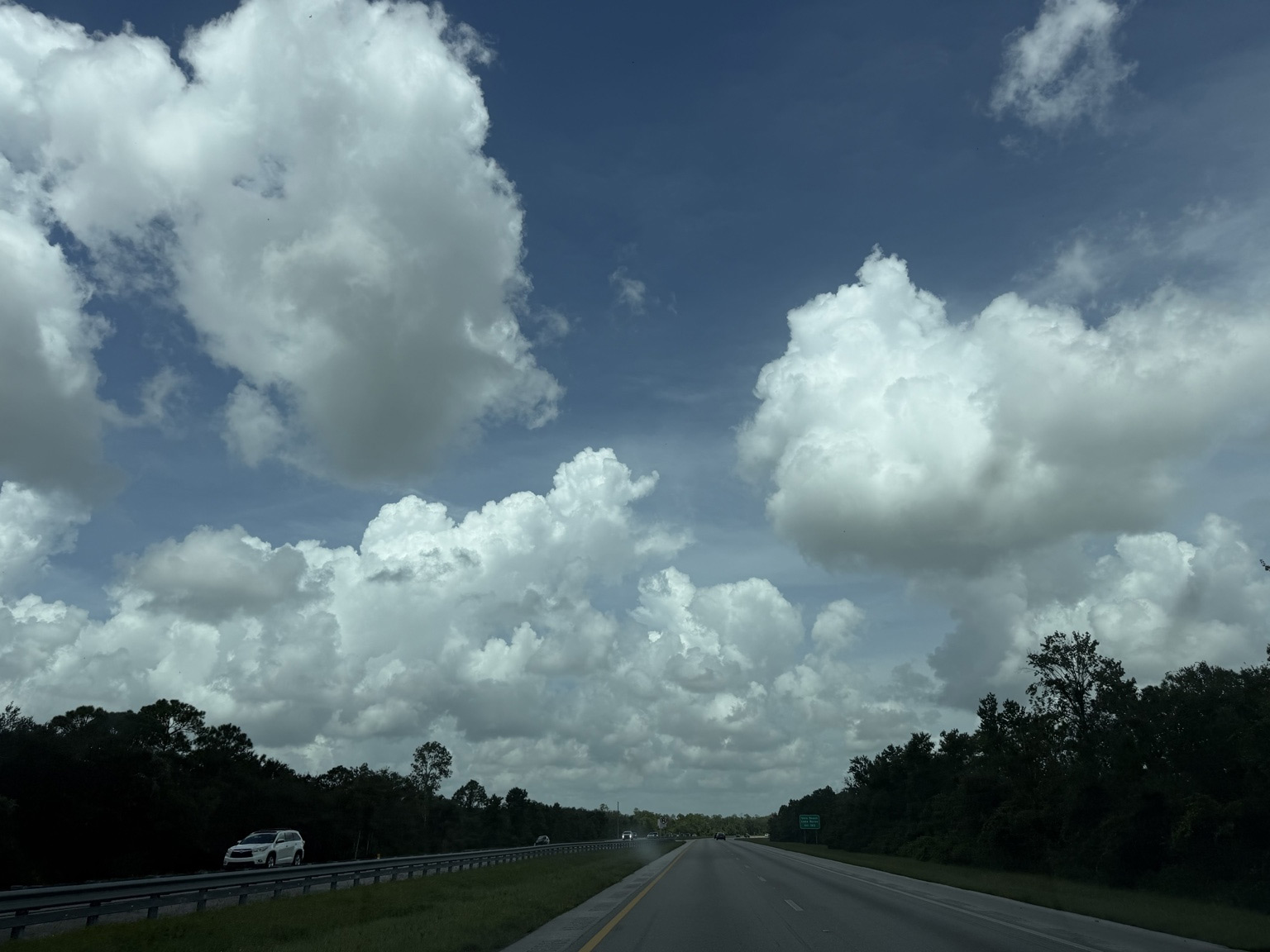 Unaltered photograph of the cloudy sky above an open highway.